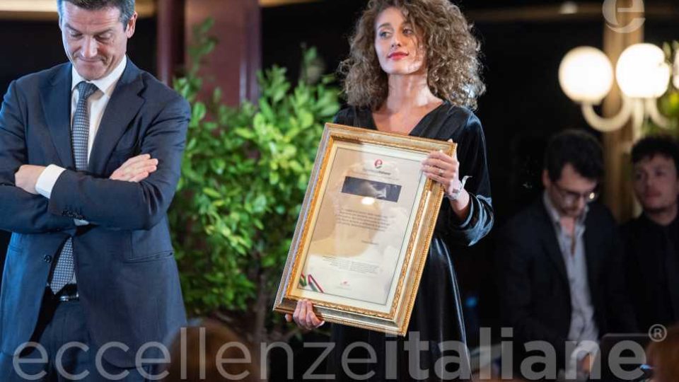 Orazio Iacono - cornice con la motivazione del premio Eccellenze Italiane retta dall' hostess